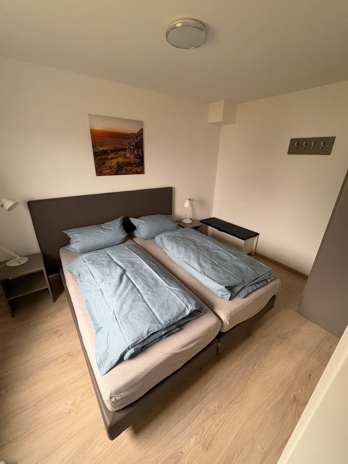 Schlafzimmer mit Doppelbett, Nachttischen und Wandbild – Ferienhaus Obernsees