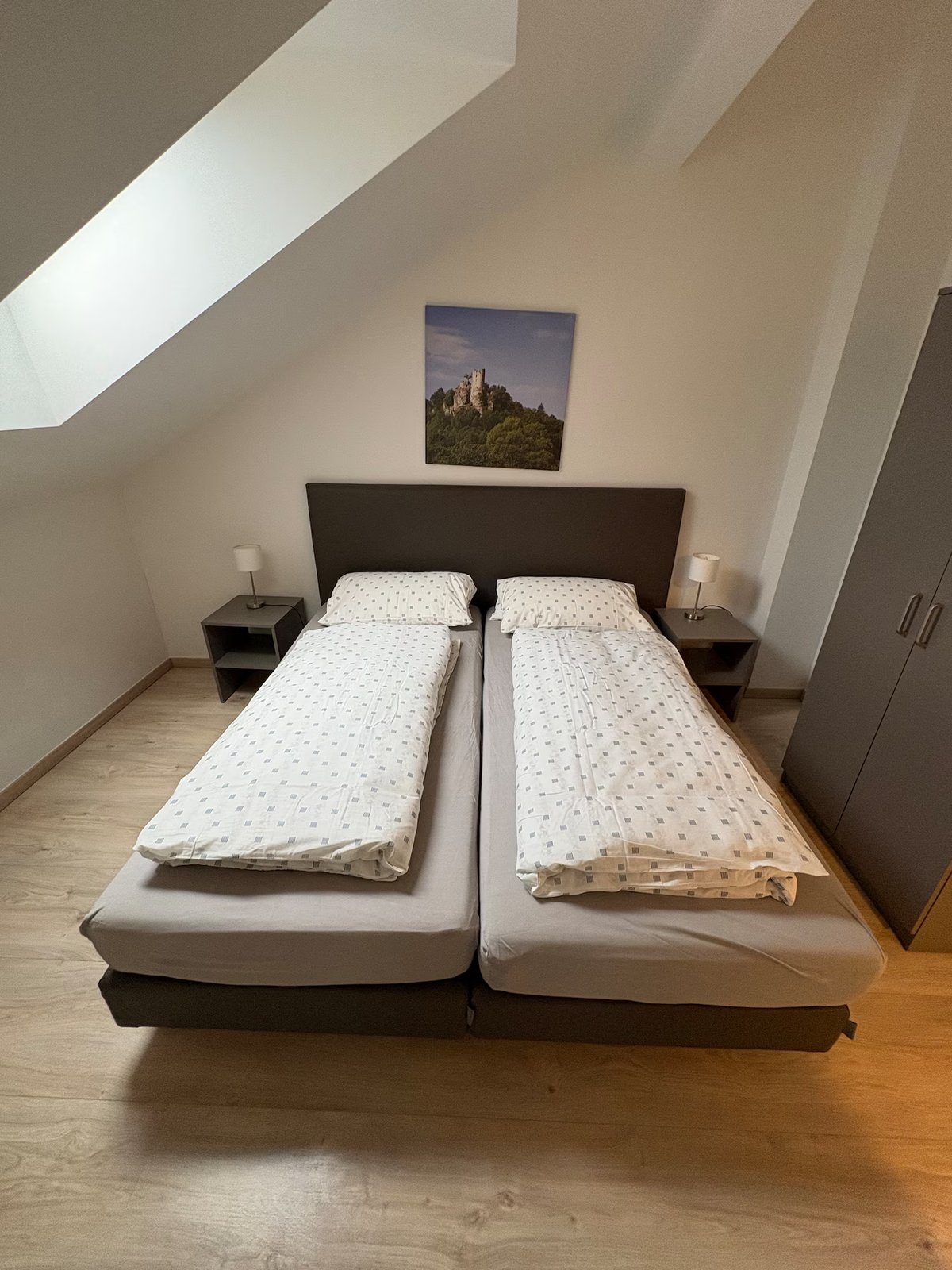 Helles Schlafzimmer im Dachgeschoss mit Dachschräge und Burgmotiv – Ferienhaus Mistelgau