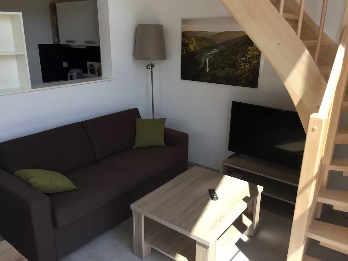 Gemütliche Sitzecke mit Sofa, Flat-TV und Wandbild der Fränkischen Schweiz – Ferienhaus an der Therme Obernsees
